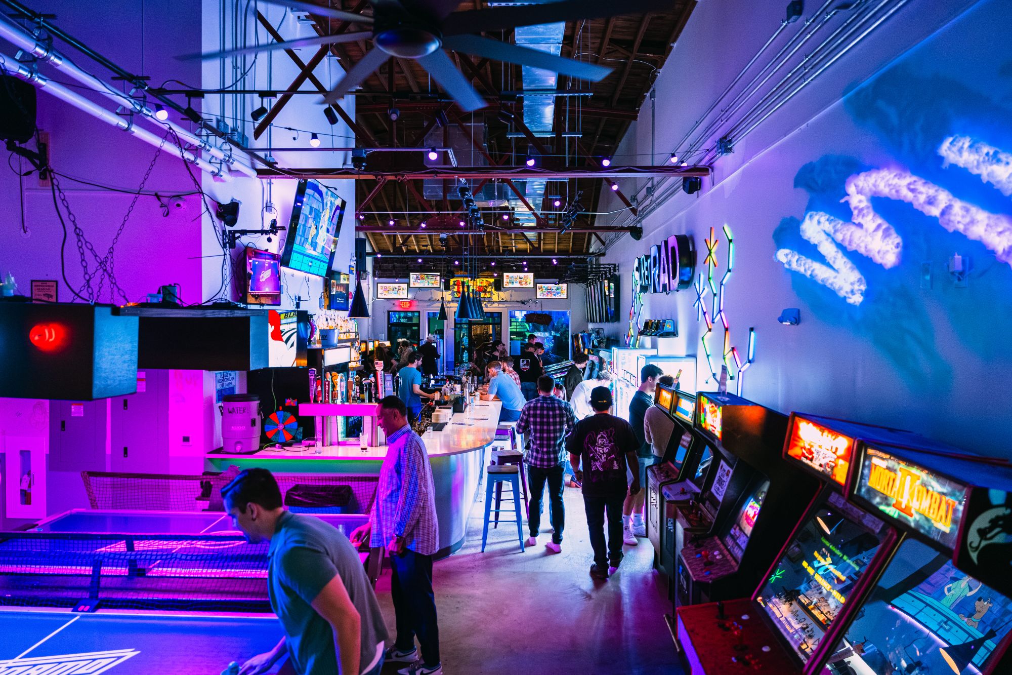 Wide shot of Super Rad arcade bar with neon glow in Raleigh NC